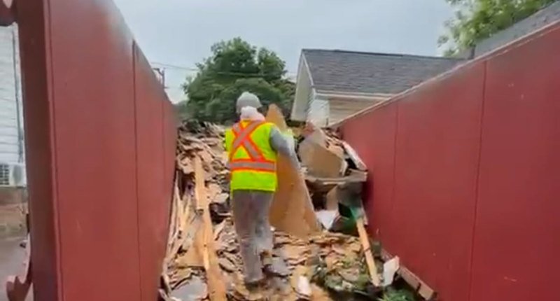 AtlantCare worker clearing construction debris into a disposal bin