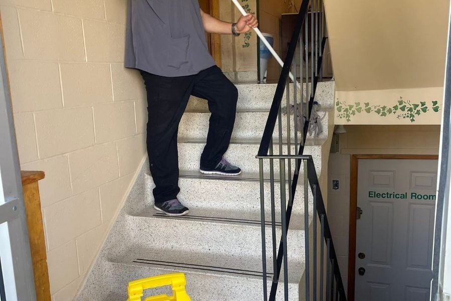 AtlantCare technician mopping a commercial stairwell with a caution sign in place