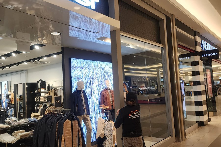 AtlantCare staff cleaning the glass storefront of a retail unit