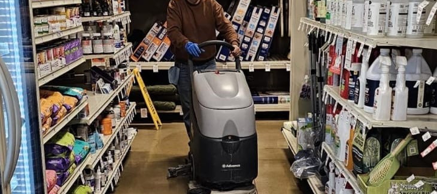AtlantCare technician running a floor scrubber along a retail store aisle